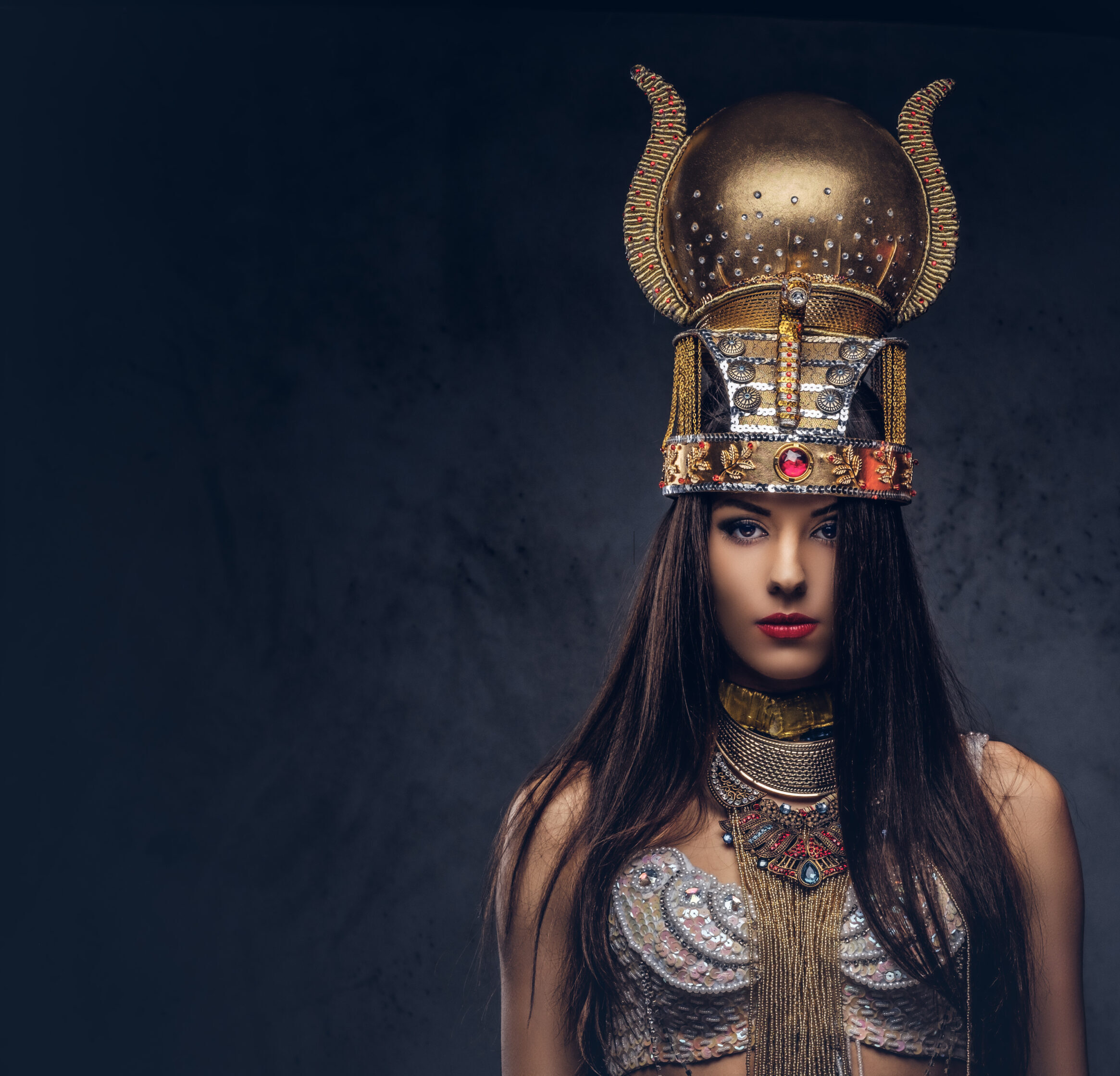 Portrait of haughty Egyptian queen in an ancient pharaoh costume. Isolated on a dark background.